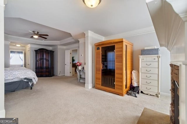 bedroom featuring light carpet, a tray ceiling, a fireplace, and crown molding