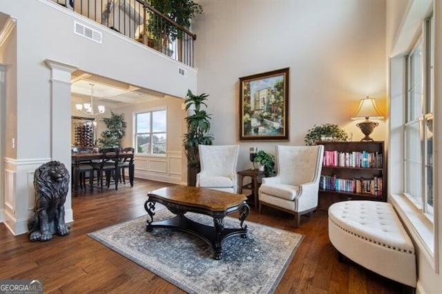 living area with a notable chandelier, a towering ceiling, and dark hardwood / wood-style floors