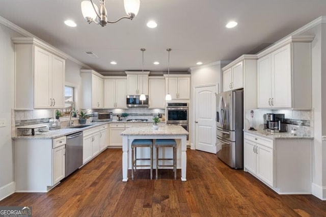 kitchen featuring appliances with stainless steel finishes, decorative light fixtures, a center island, and sink