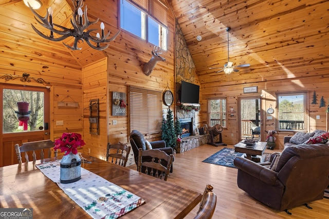 dining area featuring light hardwood / wood-style floors, a wealth of natural light, wooden walls, and a fireplace