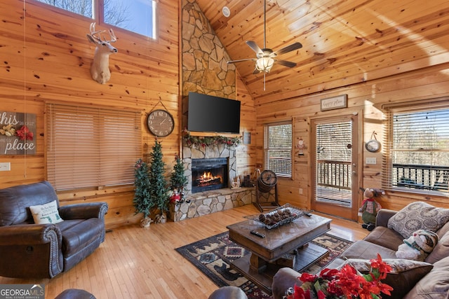 living room featuring a fireplace, light hardwood / wood-style flooring, wood walls, and wooden ceiling