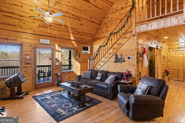 living room with high vaulted ceiling, hardwood / wood-style flooring, ceiling fan, and wood walls