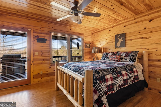 bedroom with wood ceiling, ceiling fan, hardwood / wood-style flooring, wooden walls, and access to exterior