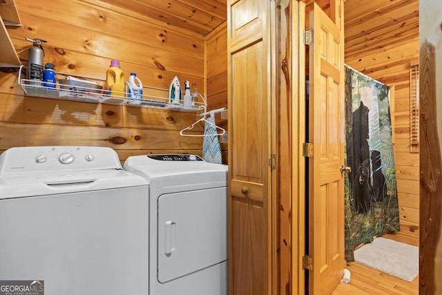 clothes washing area featuring wooden ceiling, washer and clothes dryer, wood walls, and light wood-type flooring