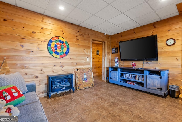 living room featuring a paneled ceiling and wood walls