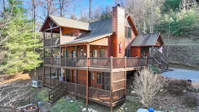 rear view of house featuring a wooden deck and a balcony