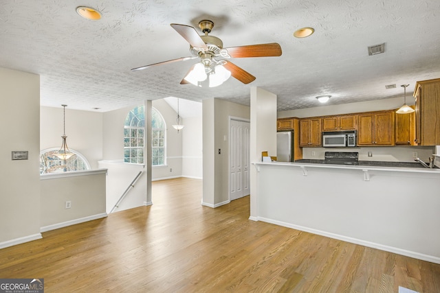 kitchen featuring kitchen peninsula, stainless steel fridge, a breakfast bar, and hanging light fixtures