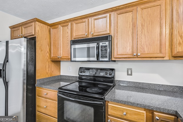 kitchen featuring dark stone counters, a textured ceiling, and appliances with stainless steel finishes