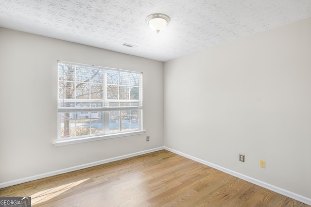 unfurnished room with light hardwood / wood-style floors and a textured ceiling