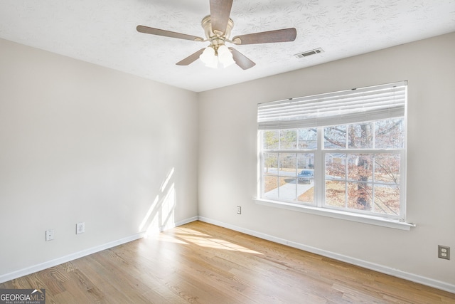 spare room featuring a textured ceiling, light wood-type flooring, and ceiling fan