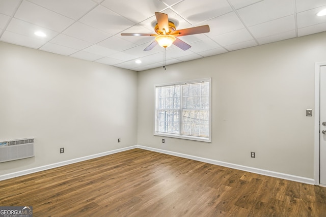 unfurnished room featuring ceiling fan, a drop ceiling, dark wood-type flooring, and a wall mounted air conditioner