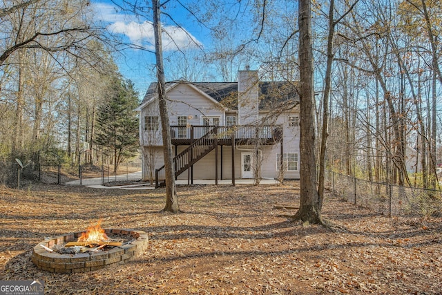 back of property featuring a fire pit and a deck