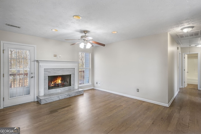 unfurnished living room with a textured ceiling, dark hardwood / wood-style floors, a healthy amount of sunlight, and a premium fireplace