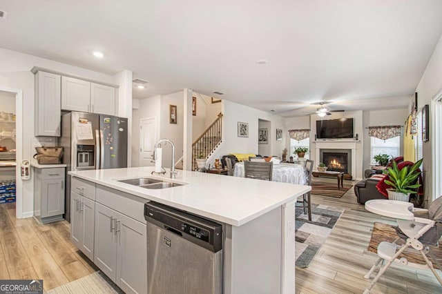 kitchen featuring ceiling fan, gray cabinets, a center island with sink, sink, and stainless steel appliances