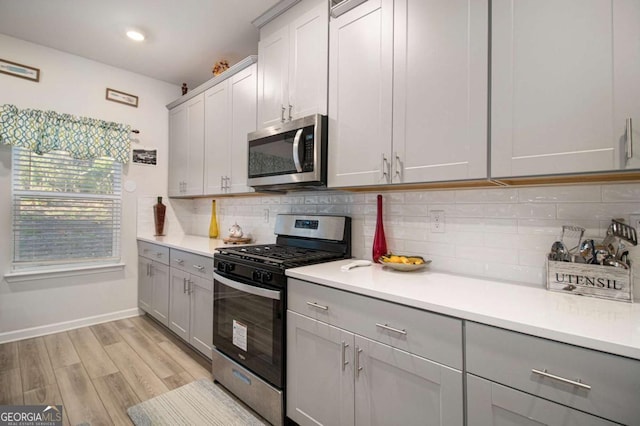 kitchen featuring tasteful backsplash, gray cabinets, stainless steel appliances, and light hardwood / wood-style floors