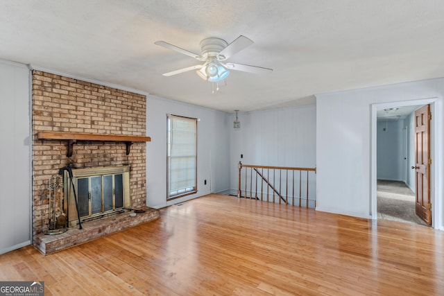 unfurnished living room with a brick fireplace, a textured ceiling, wood-type flooring, and ceiling fan