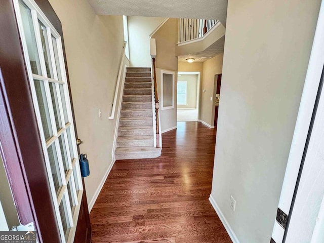 entrance foyer featuring a textured ceiling, a towering ceiling, and dark hardwood / wood-style floors