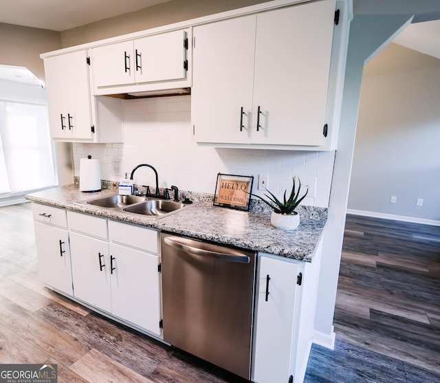 kitchen with hardwood / wood-style floors, backsplash, sink, stainless steel dishwasher, and white cabinetry