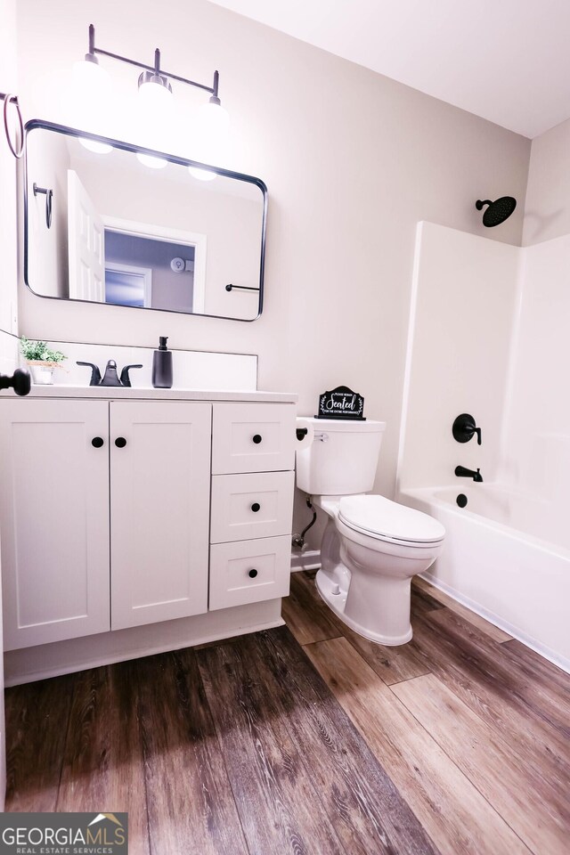 full bathroom with hardwood / wood-style flooring, vanity, toilet, and tub / shower combination