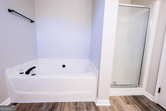 bathroom featuring hardwood / wood-style flooring and plus walk in shower