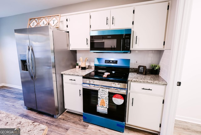 kitchen featuring white cabinets, decorative backsplash, light wood-type flooring, and appliances with stainless steel finishes