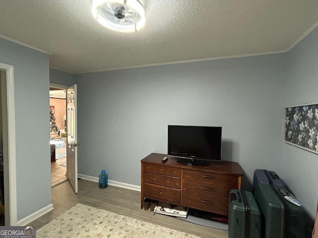 bedroom with light wood-type flooring, a textured ceiling, and ornamental molding