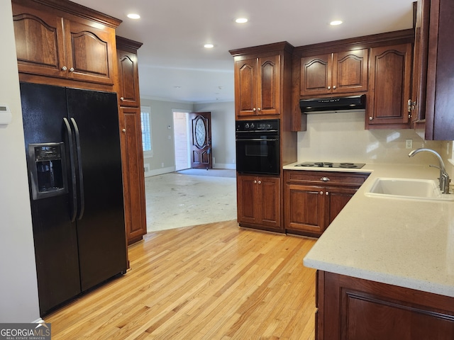 kitchen featuring sink, black appliances, and light hardwood / wood-style flooring