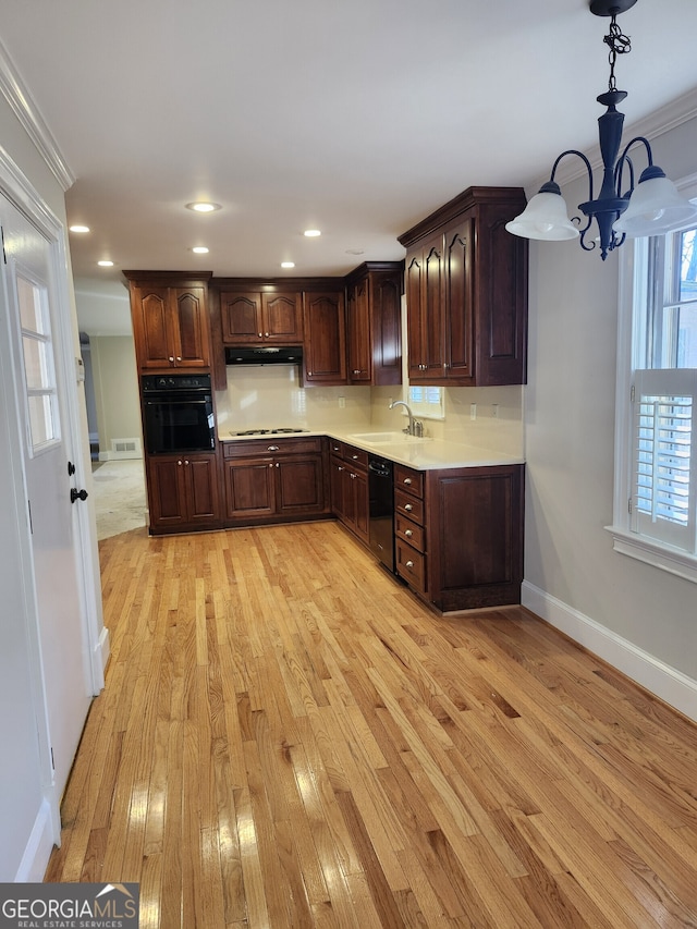 kitchen with black appliances, dark brown cabinets, sink, and hanging light fixtures