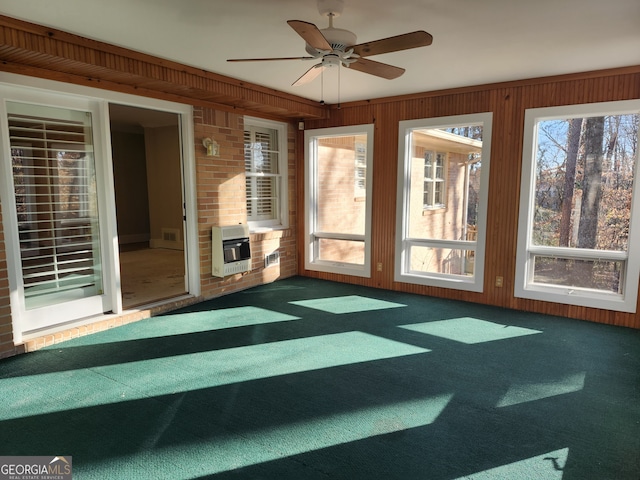 unfurnished sunroom featuring ceiling fan, a healthy amount of sunlight, and heating unit