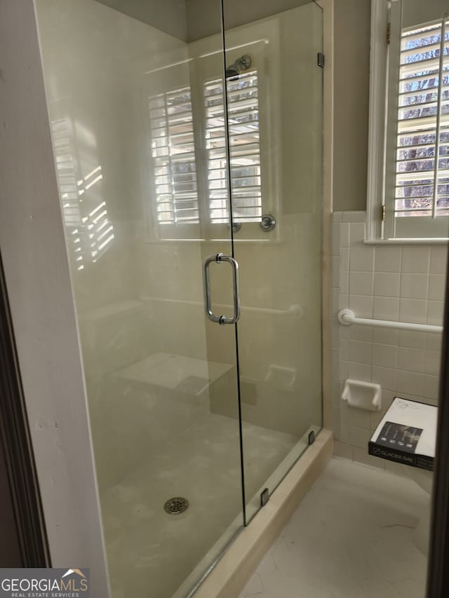 bathroom featuring radiator, backsplash, a shower with door, and tile walls