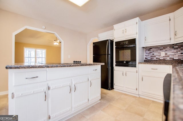 kitchen with tasteful backsplash, ceiling fan, black appliances, dark stone countertops, and white cabinetry