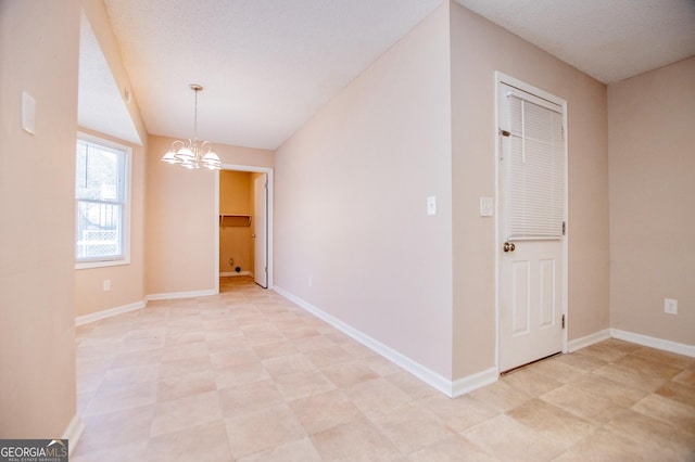 empty room featuring a textured ceiling and a notable chandelier