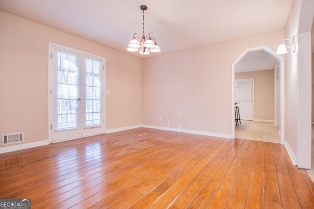 empty room with light hardwood / wood-style flooring and an inviting chandelier