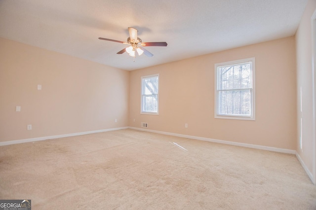 spare room with ceiling fan, light colored carpet, and a healthy amount of sunlight