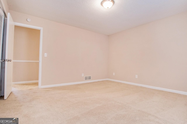 empty room featuring light carpet and a textured ceiling