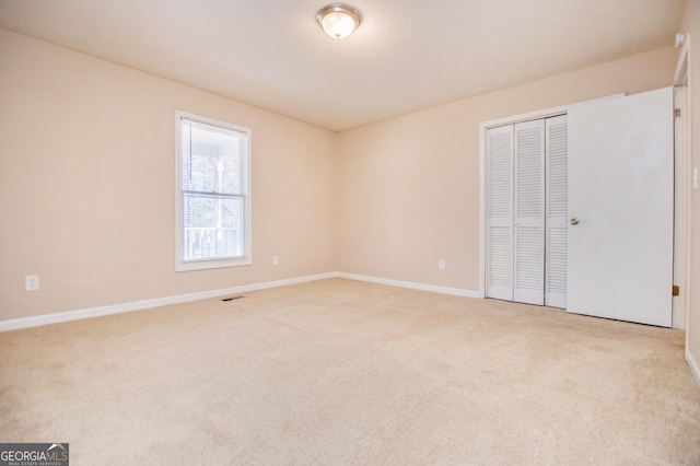 unfurnished bedroom with light carpet and a closet