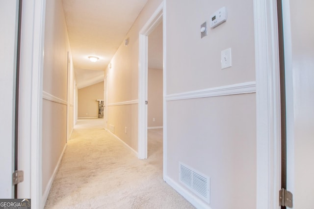 hallway with light carpet and vaulted ceiling