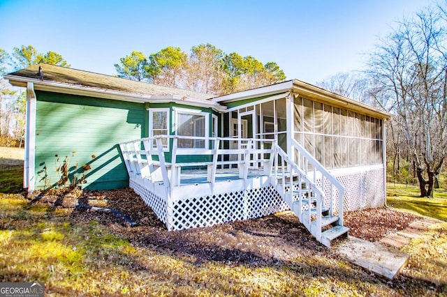 rear view of house with a sunroom and a deck