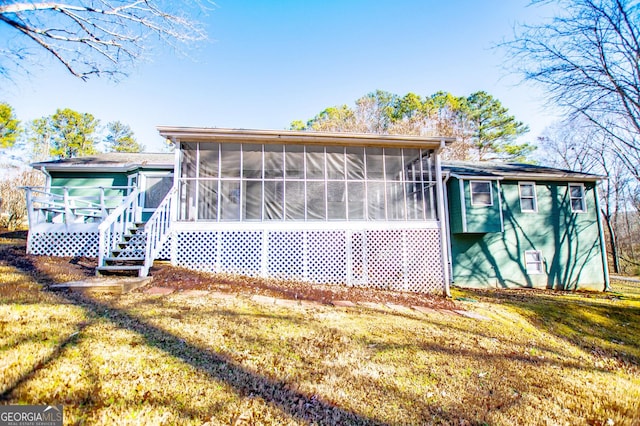 back of property featuring a sunroom and a lawn