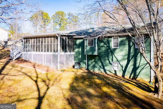 view of side of home featuring a lawn and a sunroom