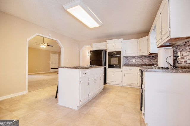 kitchen featuring white cabinetry, ceiling fan, a kitchen island, and black appliances