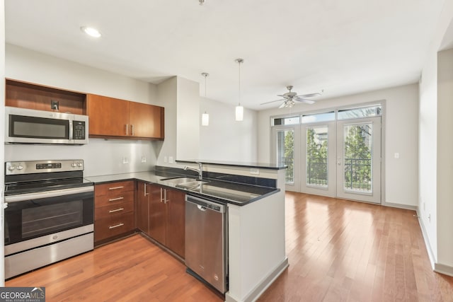 kitchen featuring pendant lighting, sink, ceiling fan, kitchen peninsula, and stainless steel appliances