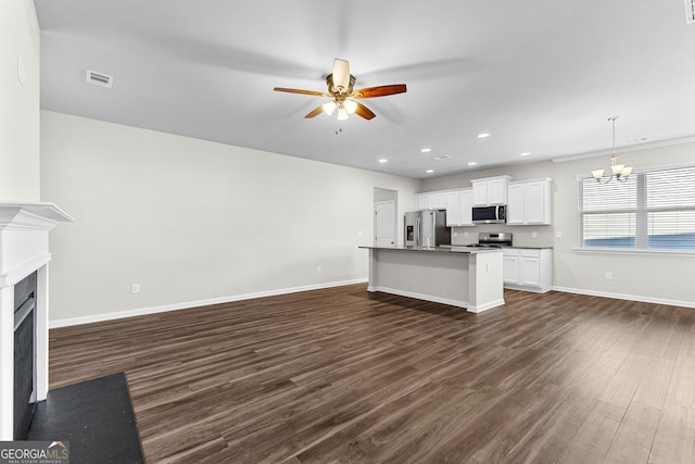 unfurnished living room with dark wood-type flooring and ceiling fan with notable chandelier