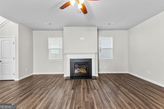 unfurnished living room featuring dark wood-type flooring, ceiling fan, and plenty of natural light