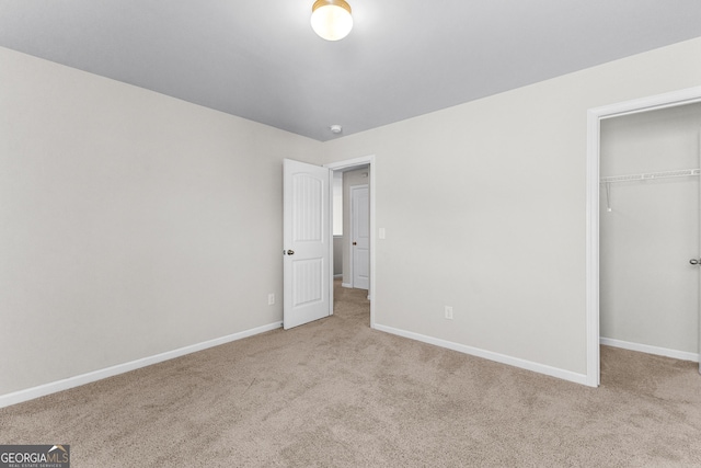 unfurnished bedroom with light colored carpet and a closet