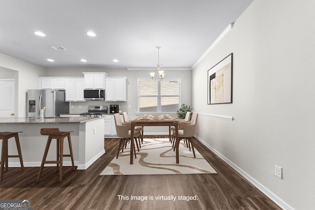 kitchen featuring pendant lighting, white cabinetry, stainless steel appliances, dark stone counters, and a breakfast bar area