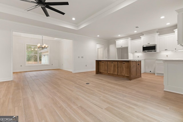 kitchen with ceiling fan with notable chandelier, light wood-style floors, stainless steel microwave, and white cabinets