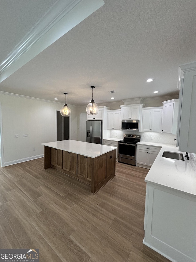 kitchen featuring wood finished floors, a kitchen island, light countertops, appliances with stainless steel finishes, and white cabinetry