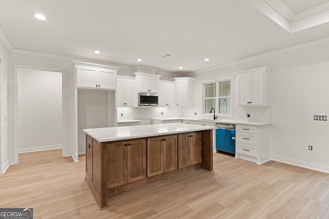 kitchen featuring crown molding, stainless steel microwave, white cabinets, a sink, and dishwasher