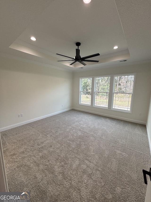 carpeted spare room featuring a tray ceiling, recessed lighting, crown molding, and baseboards